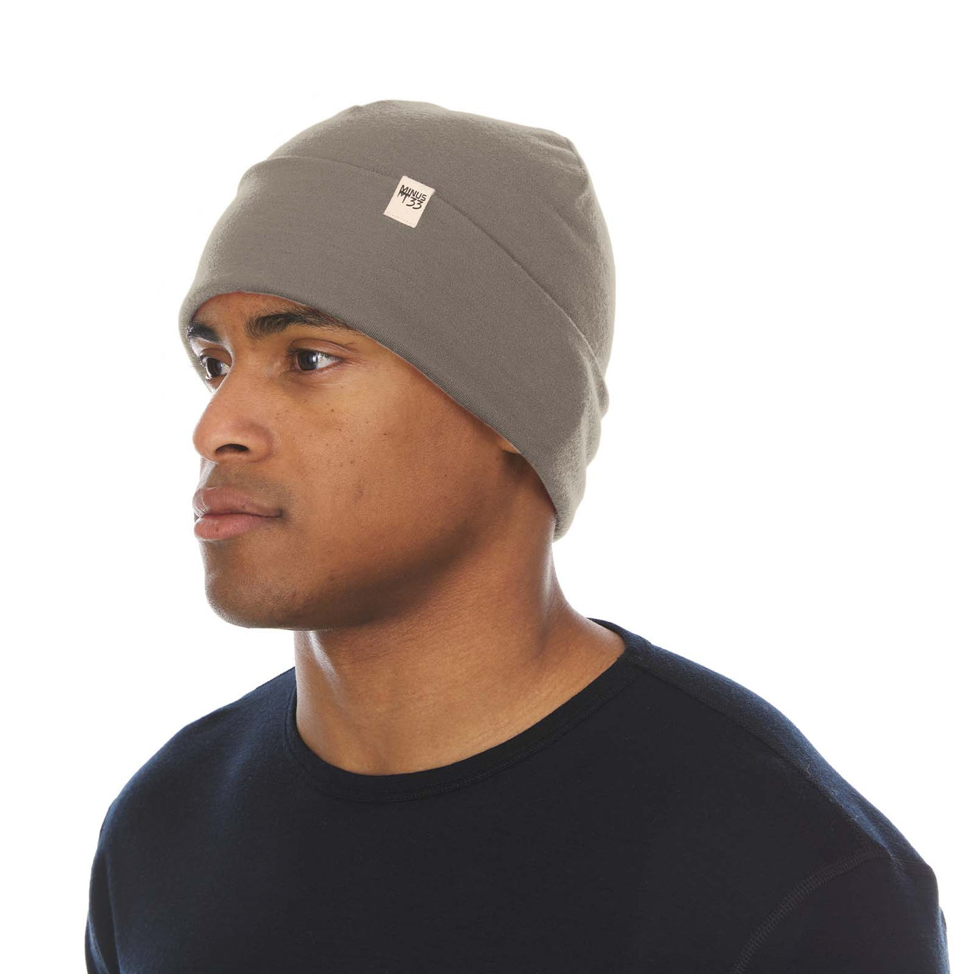 Minus33 Ridge Cuff Merino Wool Beanie in Tan 499 worn by a man on a neutral background.