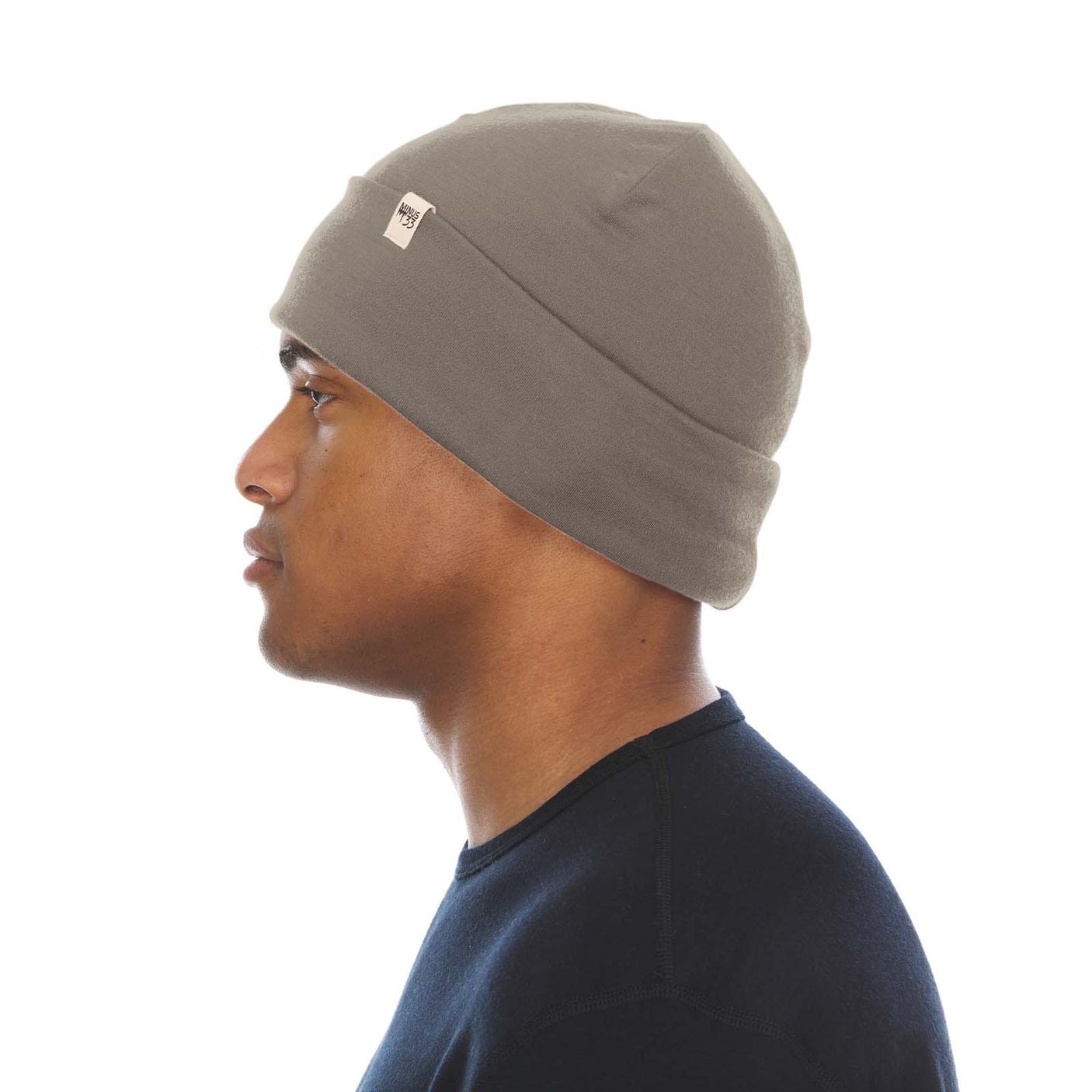 Minus33 Ridge Cuff Merino Wool Beanie in Tan 499 worn by a man on a neutral background.