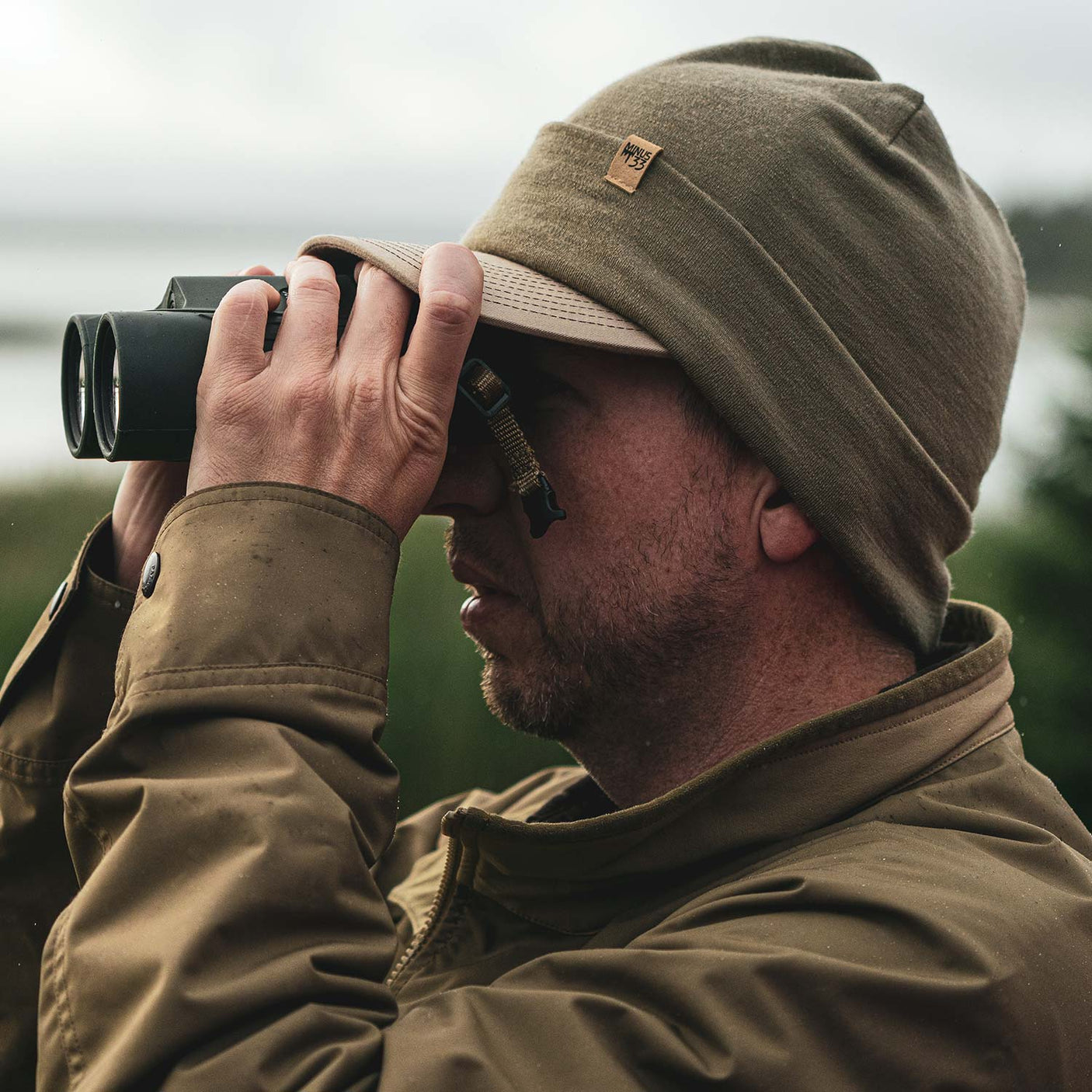 Minus33 Ridge Cuff Merino Wool Beanie in Tan 499 worn by a man outdoors.