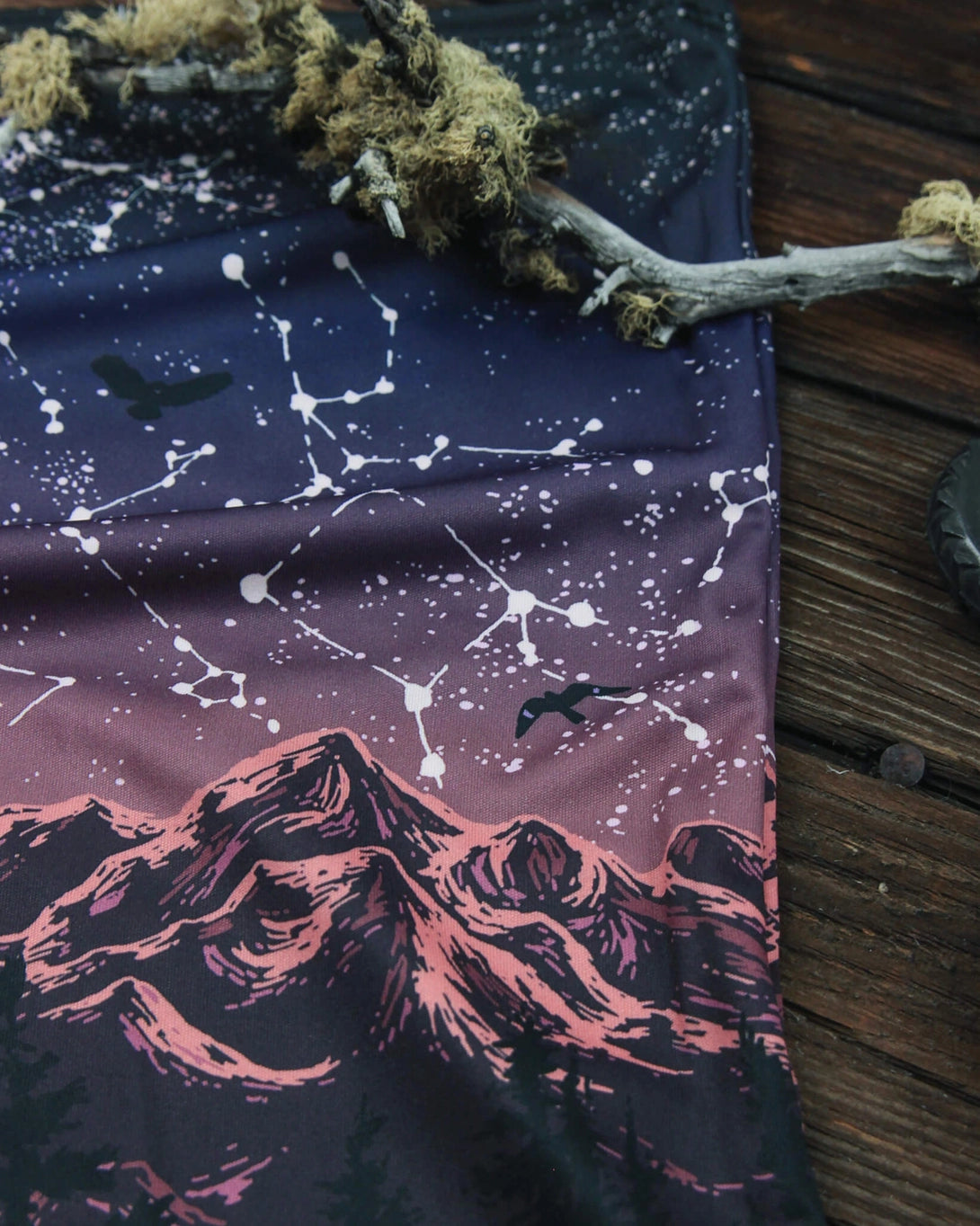 Closeup of Alpinecho's Stargazer Neck Gaiter in Plum on a dark wood background.