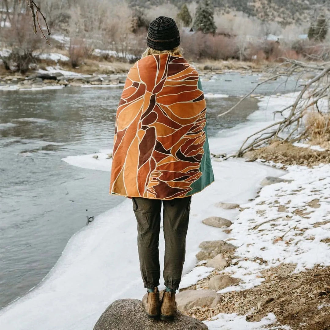 Trek Light Alpenglow Wander towel is made from recycled plastic bottles and features an abstract depiction of the mountains and sun.