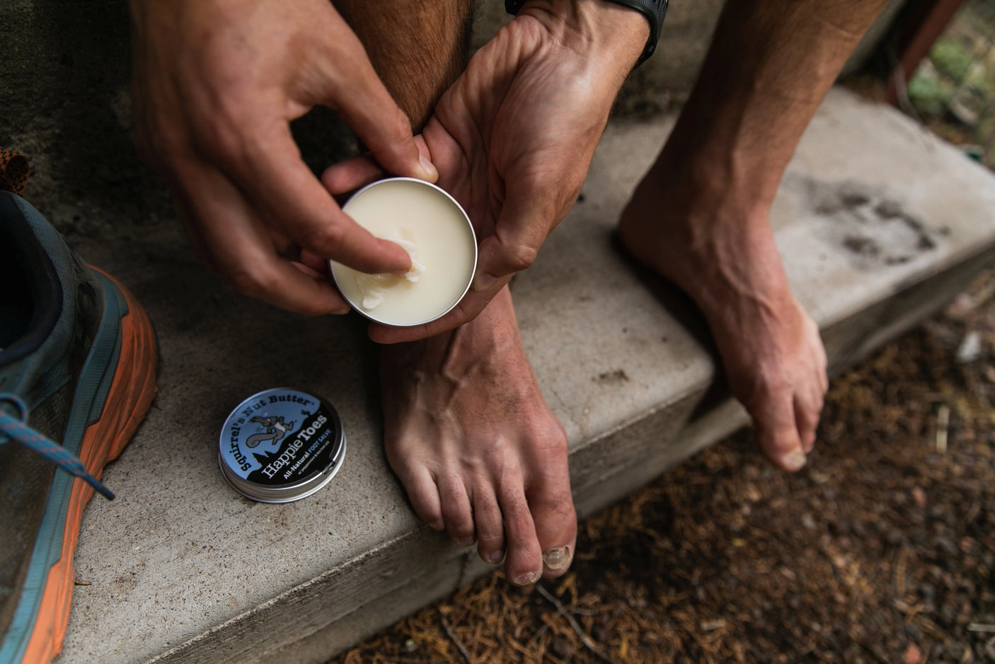 Individual pulling Squirrel's Nut Butter Happie Toes balm from the tin.