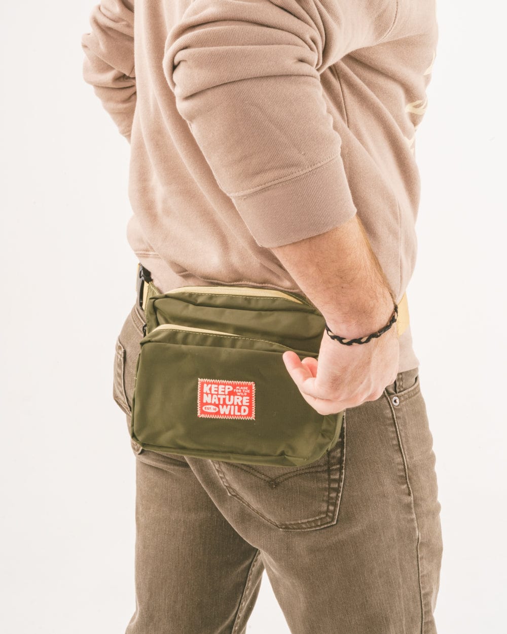 Keep Nature Wild adventure fanny pack in olive green with a stitched on Keep Nature Wild logo patch on the front.
