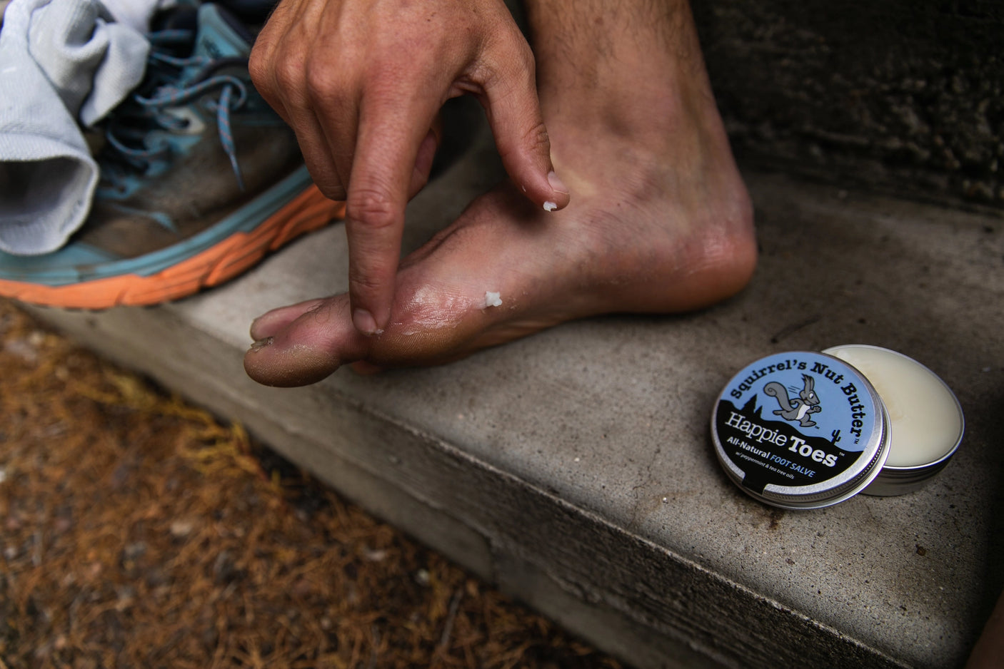 Individual applying Squirrel's Nut Butter Happie Toes salve to their foot.