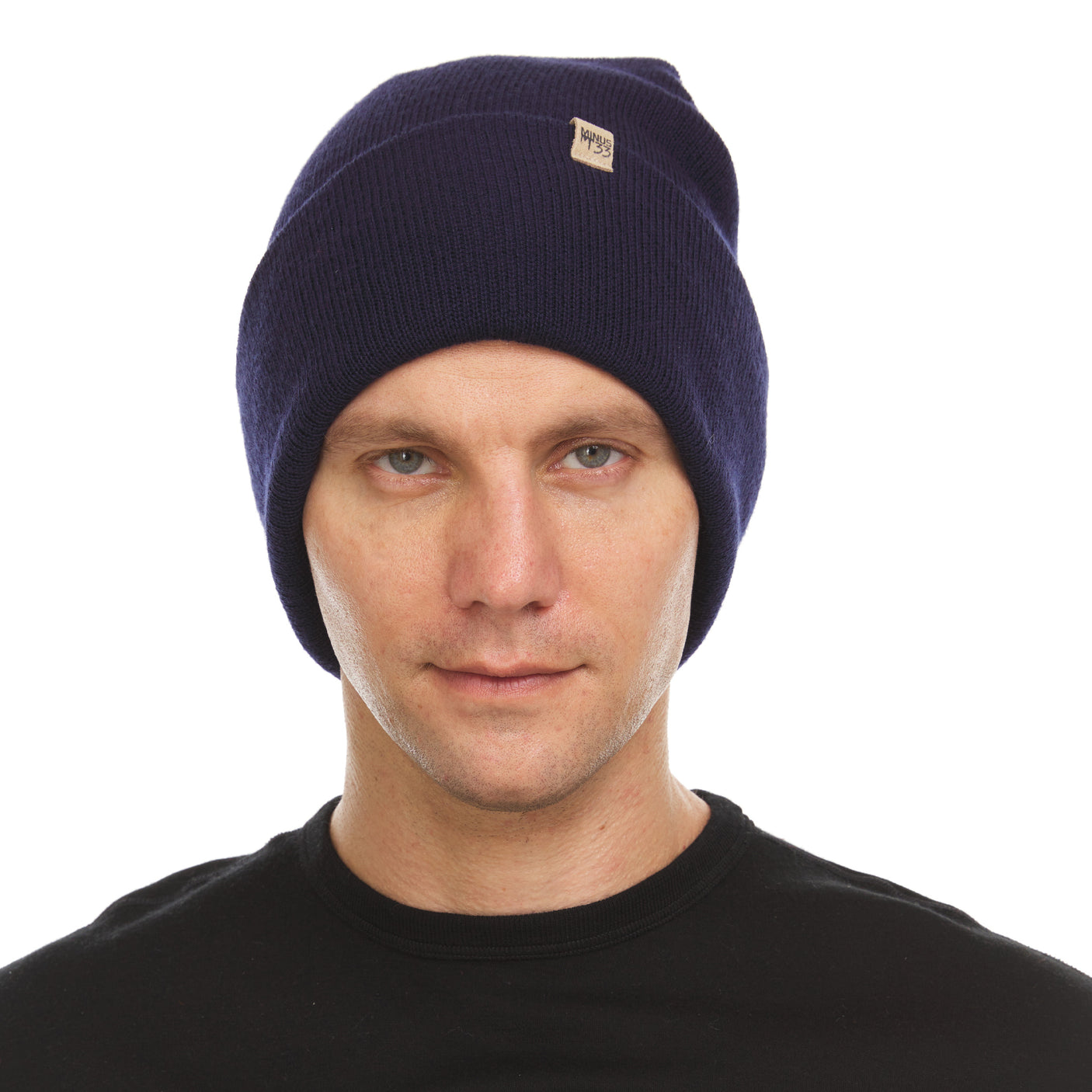 Minus33 Everyday Knit Cuff Merino Wool Beanie in Navy being worn on a neutral background.