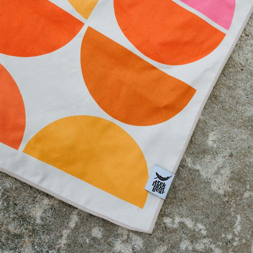 Trek Light Half Moon Wander towel is made from recycled plastic bottles and features a colorful half moon pattern.