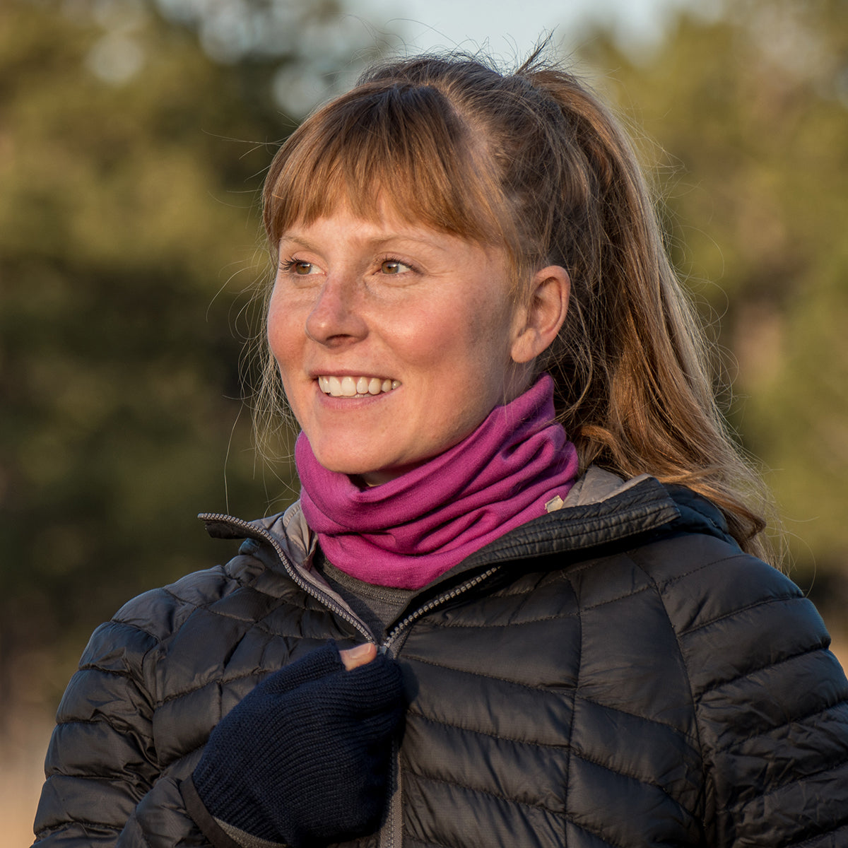 Minus33 Midweight - Neck Gaiter 100% Merino Wool in Radiant Violet being worn by a woman outdoors.