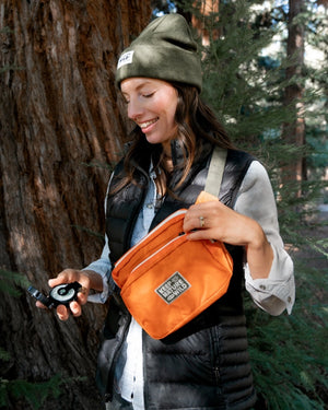 KNW Fanny Pack worn as a sling bag by a woman in the woods.