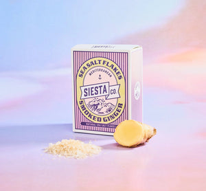 Box of Siesta Co. Ginger Sea Salt Flakes with a lemon and salt flakes on a gradient background