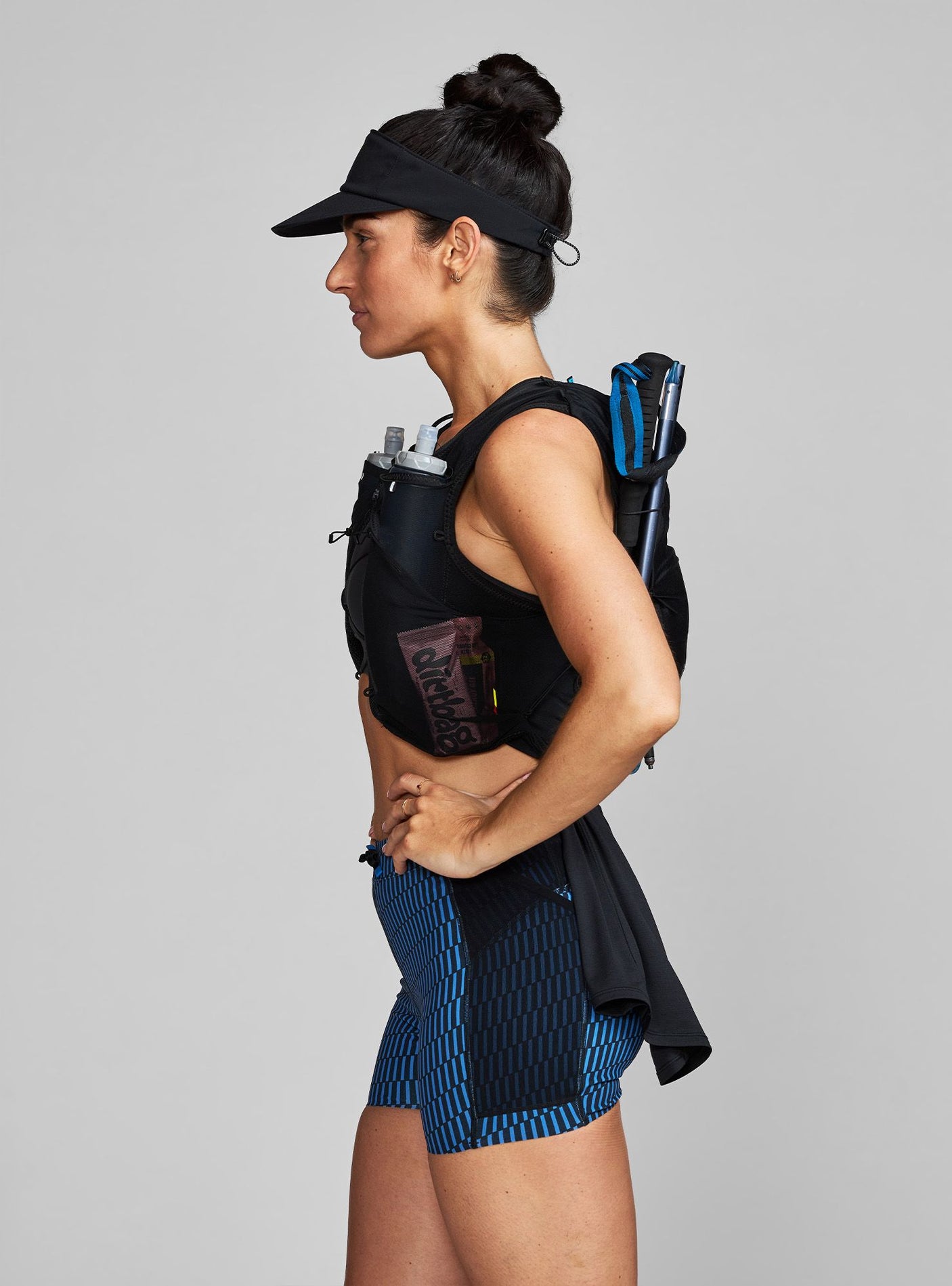 Janji AFO Hyperlight Visor on a neutral background worn by a woman in a trail running vest.
