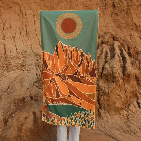 Trek Light Alpenglow Wander towel is made from recycled plastic bottles and features an abstract depiction of the mountains and sun.