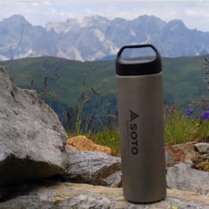 SOTO Titanium Bottle 300ml, ultralight bottle outdoors in a mountain scene.