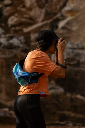 Janji's Circa Boxy Daily Tee in Amphora being worn by a woman taking a picture.