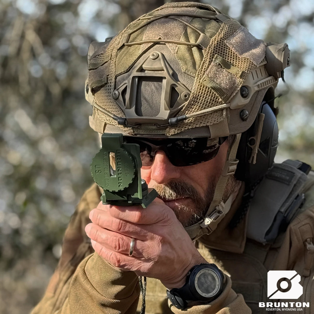 Person in tactical gear using a Brunton H-3 Tritium Lensatic Compass outdoors