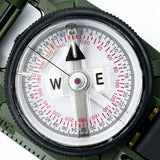 Close-up of a Brunton H-3 Tritium Lensatic Compass with a white face and black rim on a green background