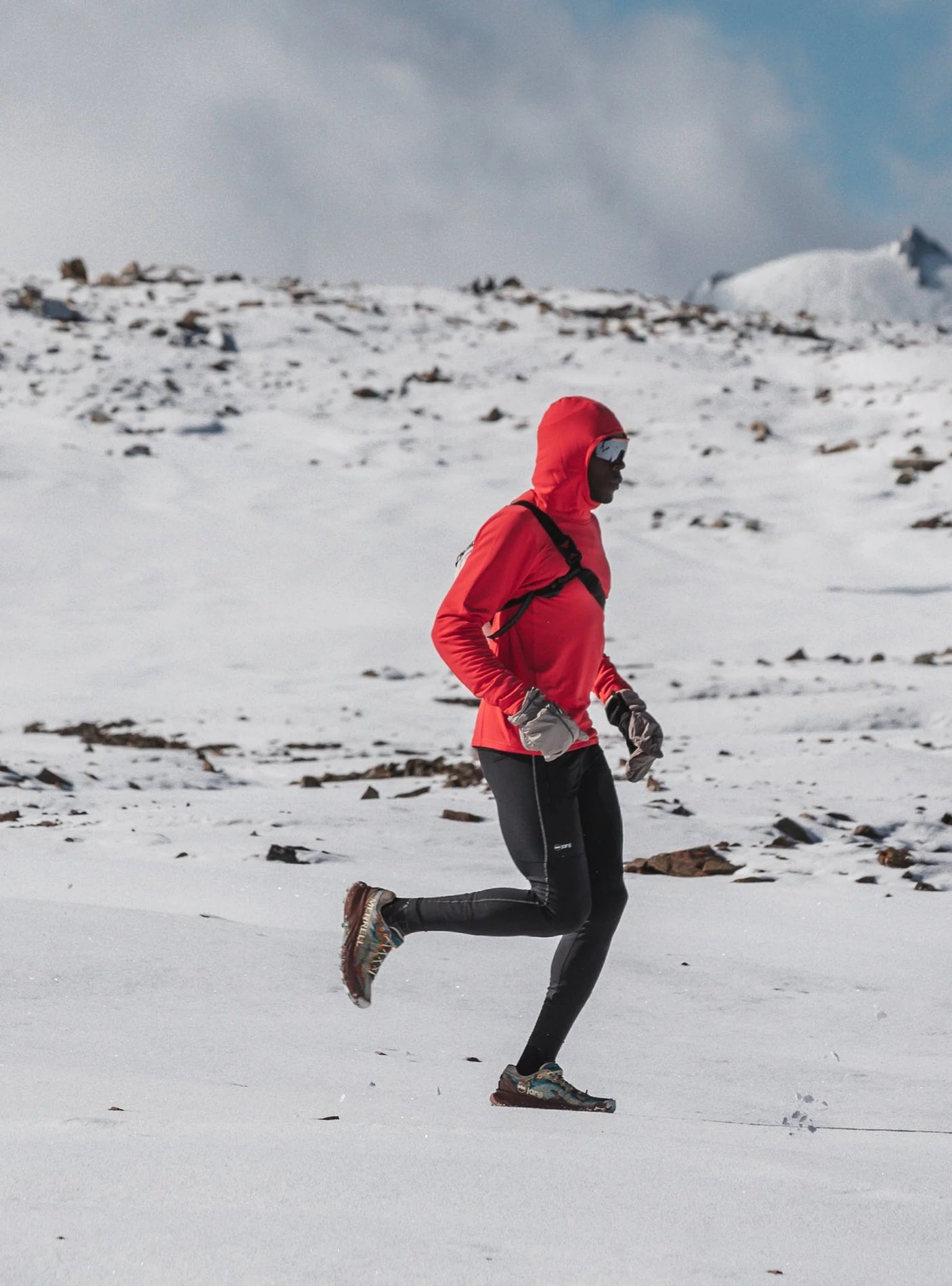 Janji M's Rover Merino Hoodie in Nova worn by a man in the snow.