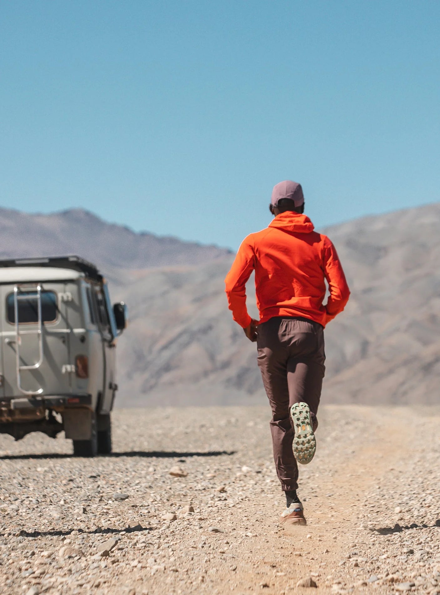 Janji M's Rover Merino Hoodie in Nova worn by a man in the snow.