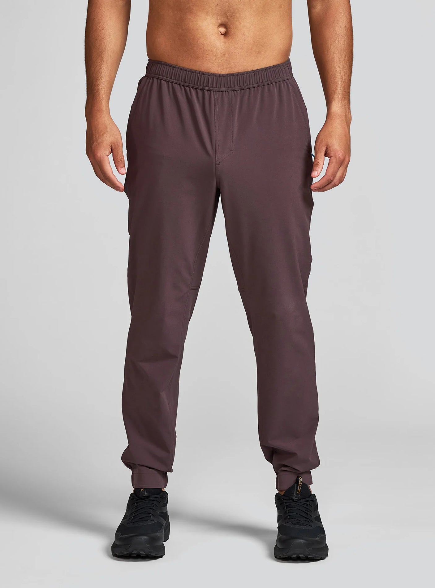 Janji Men's Transit Tech Pant in Loam worn by a man on a neutral background.