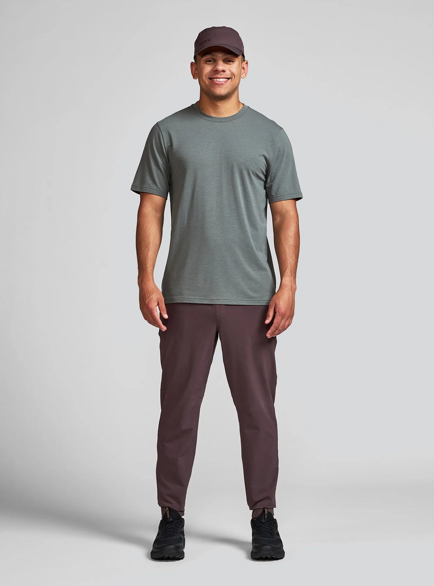 Janji Men's Transit Tech Pant in Loam worn by a man on a neutral background.