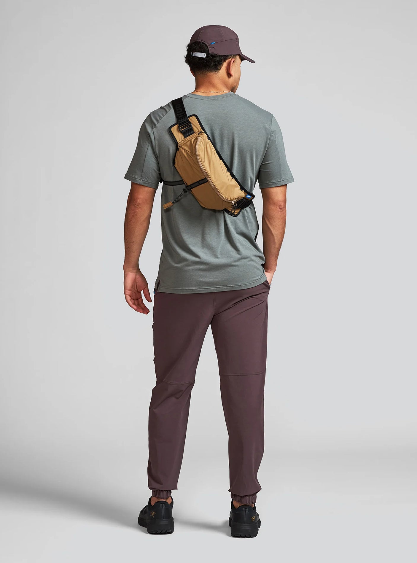 Janji Men's Transit Tech Pant in Loam worn by a man from the rear on a neutral background.