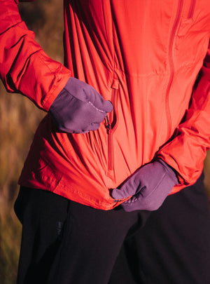 Janji W's Zephyrunner Wind Shell in Nova being worn outdoors and showing the side pocket.