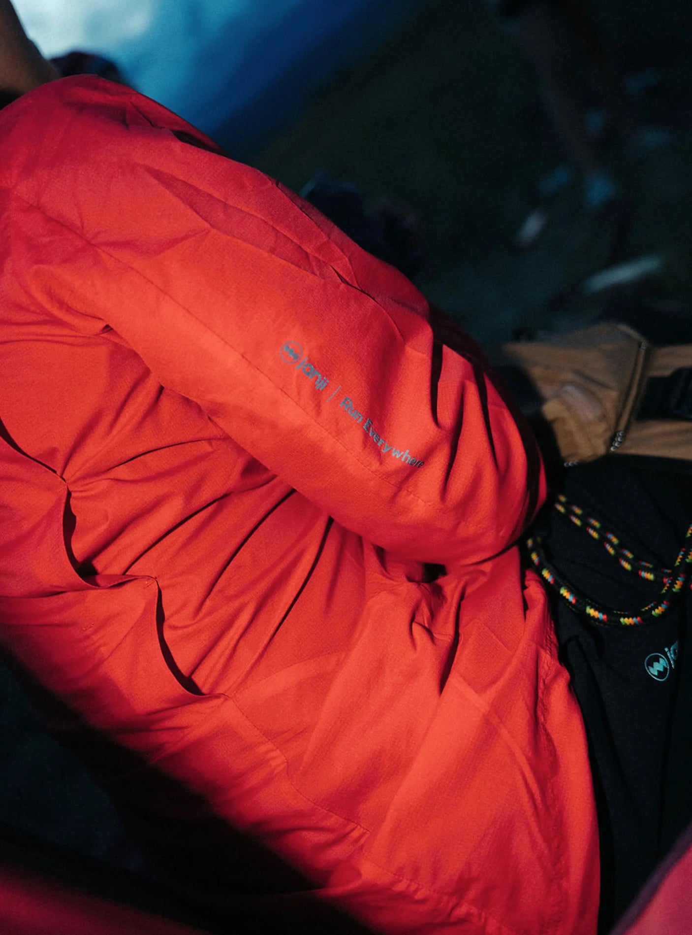 Janji W's Zephyrunner Wind Shell in Nova being worn by a woman from the side outdoors.