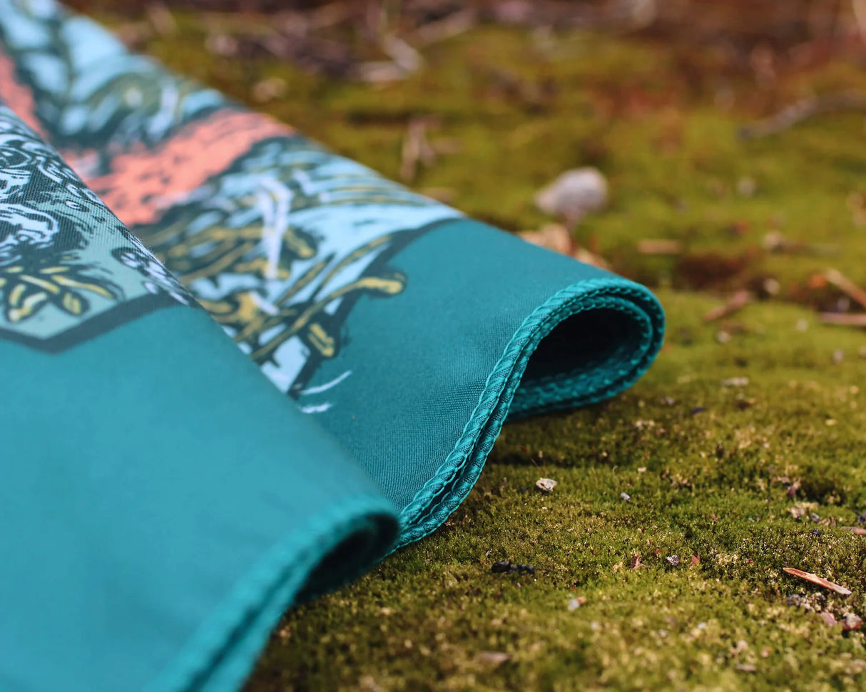 Alpinecho Tide Pool quick-dry bandana on a nature background.