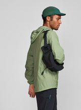 Janji Multipass Sling Bag on a neutral background being worn by a man as a sling.