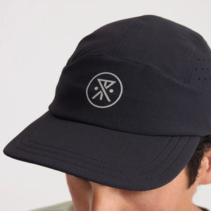 Roark Alta Elite Run Hat Strapback Hat in Black with a logo worn by a person on a light gray background