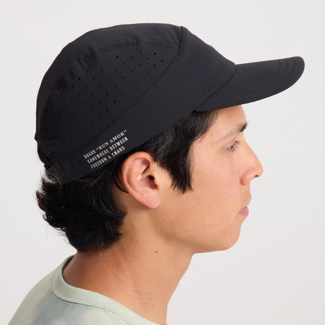 Person wearing a Roark Alta Elite Run Hat Strapback Hat in Black with text on a light gray background