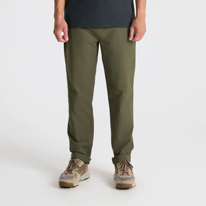 Person wearing Roark Layover Pro Traveler Pants in Military and brown shoes on a white background