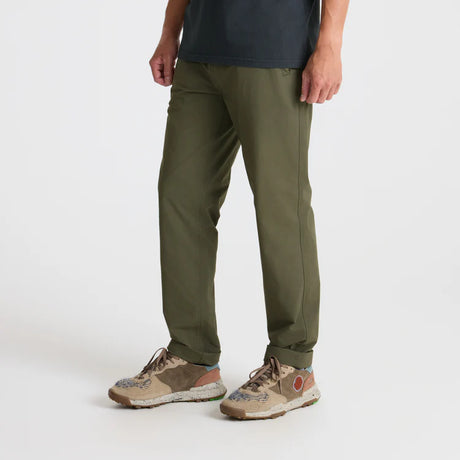 Person wearing Roark Layover Pro Traveler Pants in Military and patterned shoes on a white background
