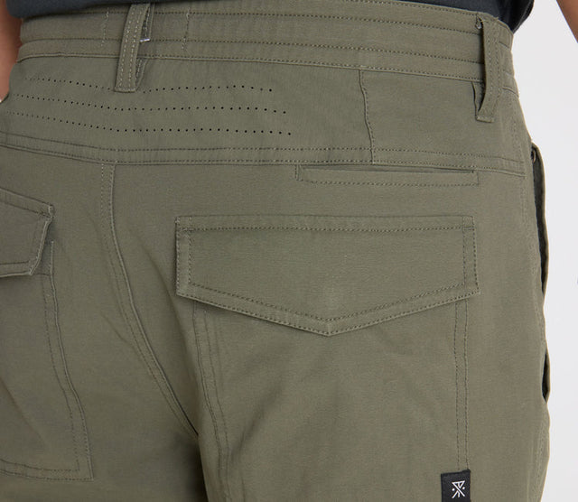 Close-up of Roark Layover Pro Traveler Pants in Military with a visible brand logo on a white background