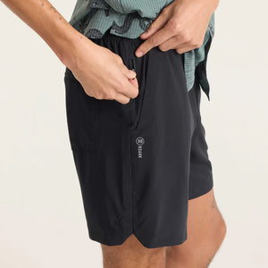 Person wearing Roark Serrano 7" Active Stretch Shorts in Black with a brand logo on a plain background