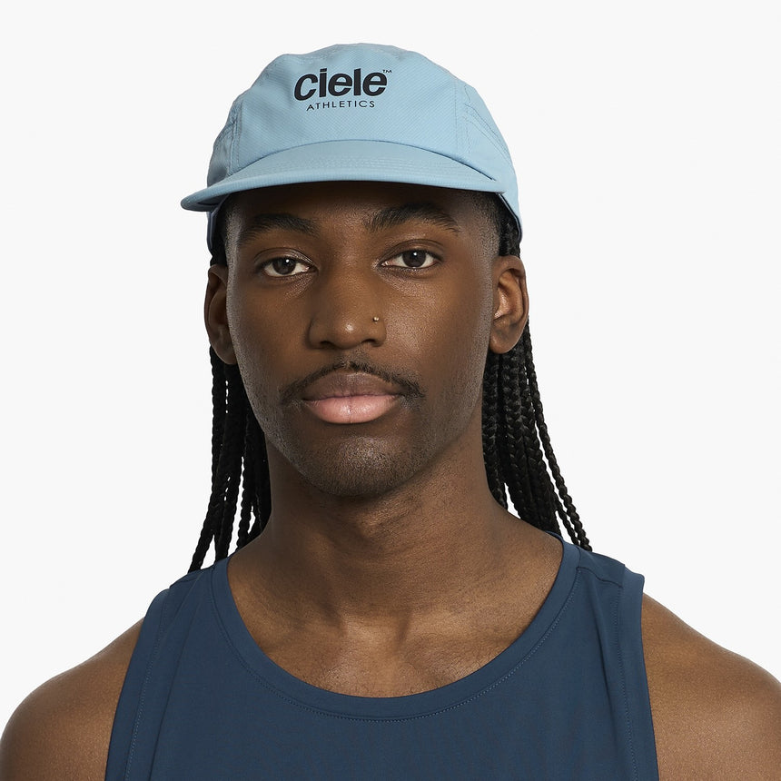 Person wearing a Ciele Athletics GOCap Classic - Athletics Chambray blue running cap with 'Ciele Athletics' logo on a white background