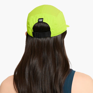 Person wearing a Ciele Athletics GOCap Classic - Athletics Lime Green running cap with a visible brand logo on a white background