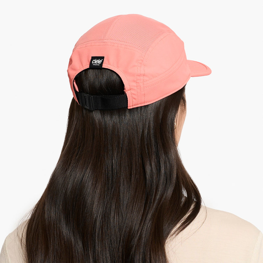 Person wearing a Ciele Athletics GOCap Classic - Athletics Blossom Coral running cap with a visible brand logo on a white background