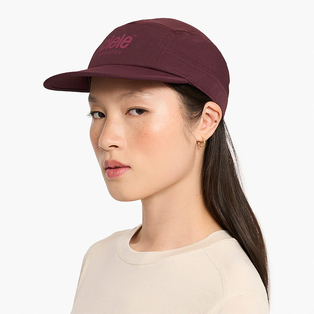Woman wearing a maroon ciele athletics GOCap Classic - Athletics in Dark Wine Red with a brand logo on a white background