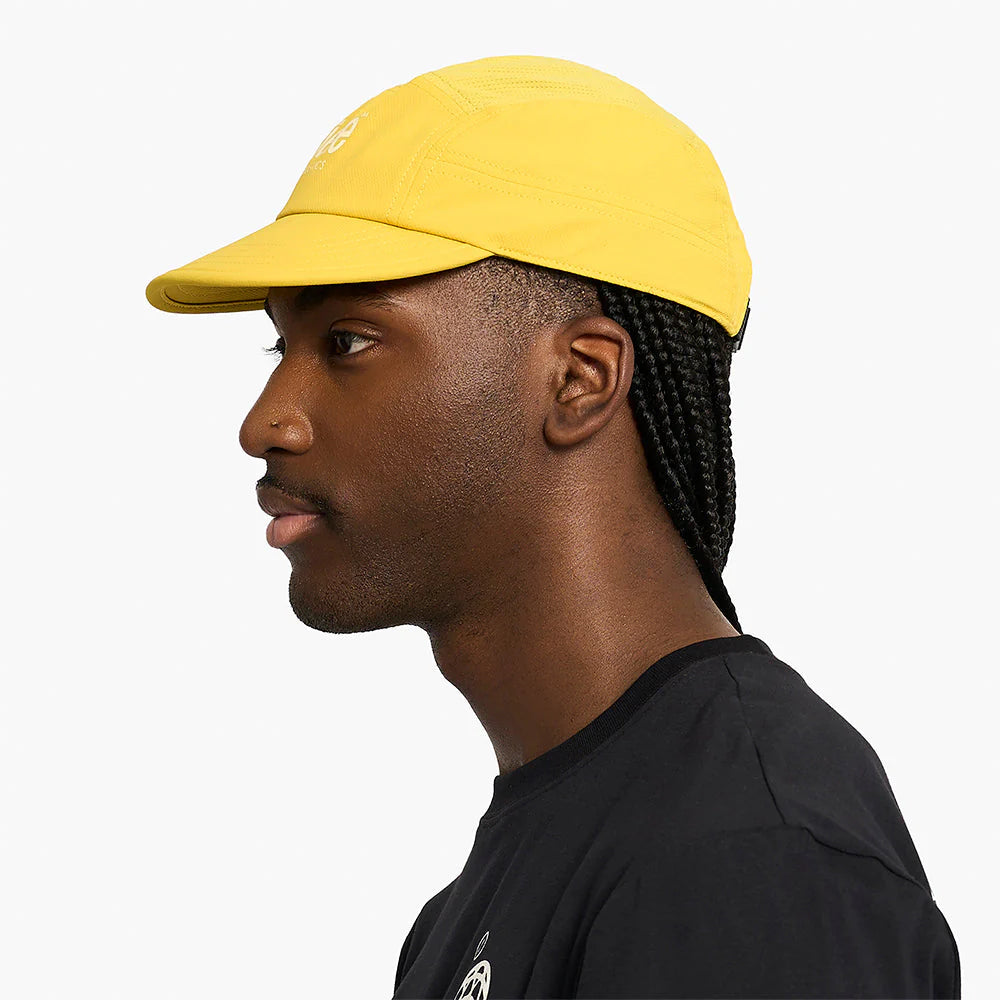 Man wearing a yellow ciele athletics GOCap Classic - Athletics in Sulfur and black shirt on a white background