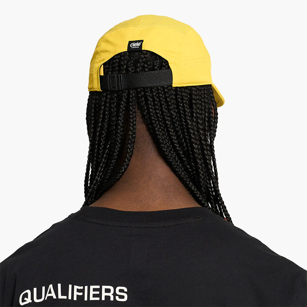 Person wearing a yellow ciele athletics GOCap Classic - Athletics in Sulfur with a black strap, back view, on a white background