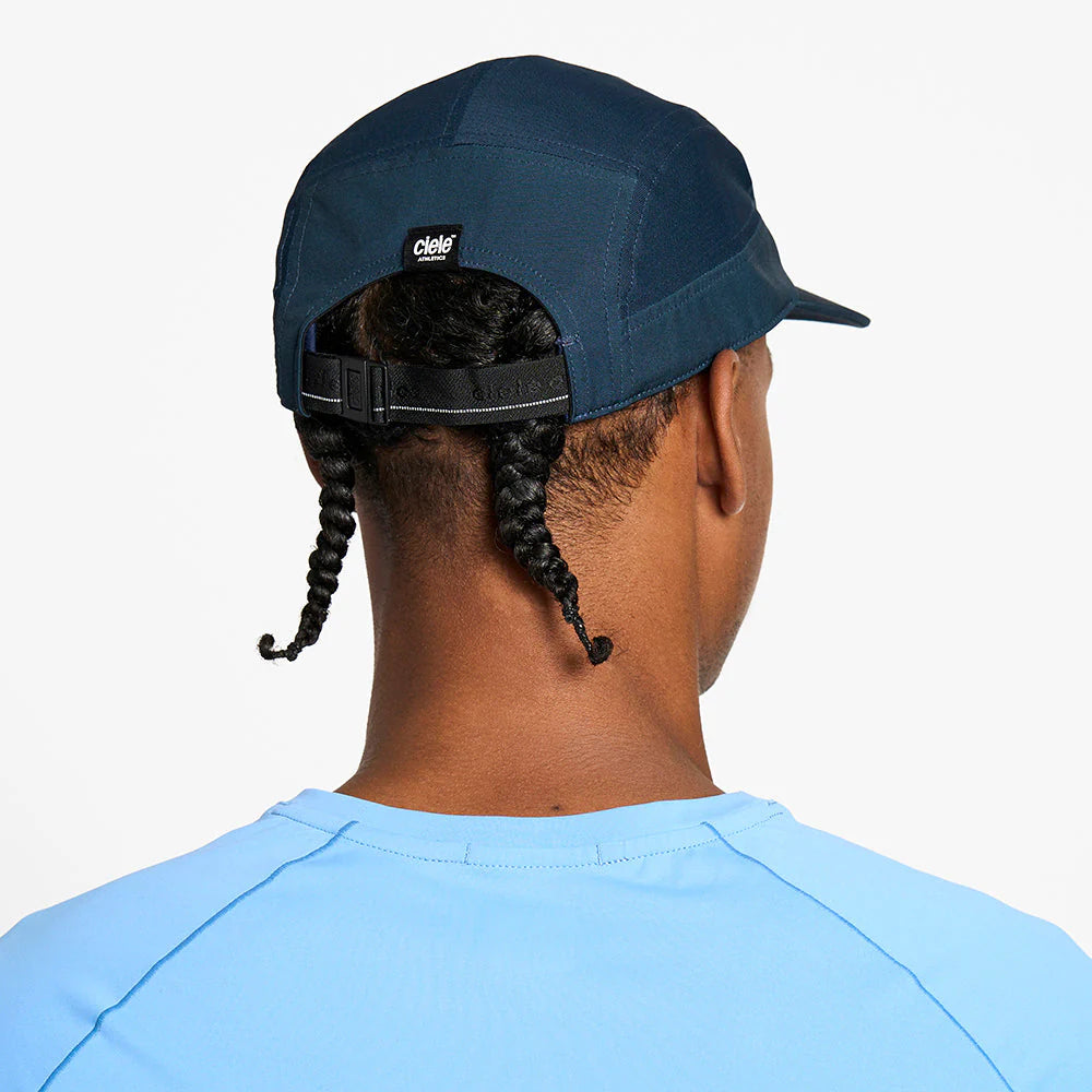 Person wearing a blue ciele athletics GOCap Comp - Century in Deep Space with a visible brand logo on a white background
