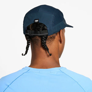 Person wearing a blue ciele athletics GOCap Comp - Century in Deep Space with a visible brand logo on a white background