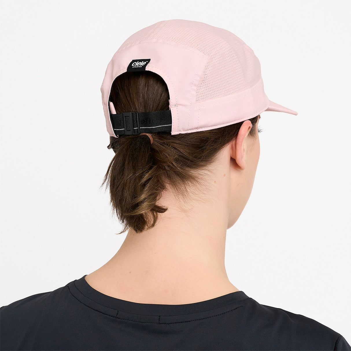 Person wearing Ciele Athletics GOCap Comp Century Peachskin pink running cap with a visible brand logo on a white background