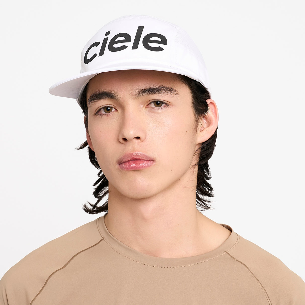Person wearing a Ciele Athletics GOCap Comp Century Trooper white running cap with 'ciele' branding on a white background