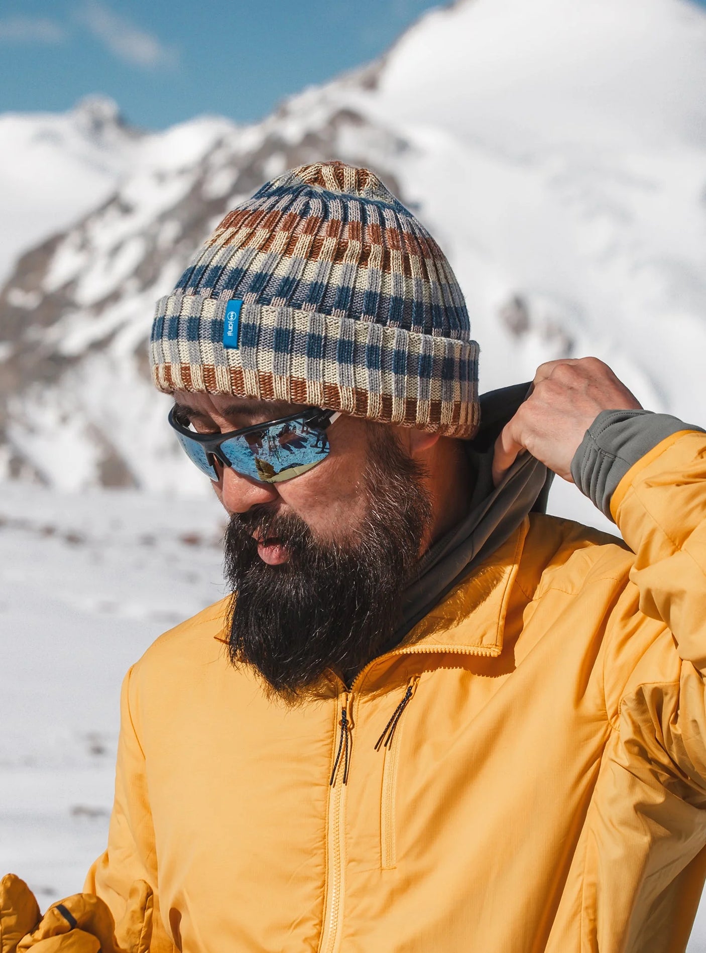 Janji Off-Grid Plaited Beanie in Dune worn by a man in the mountains.