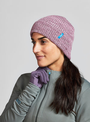 Janji Threshold Melange Beanie in Wild Shrub worn by a woman on a neutral background.