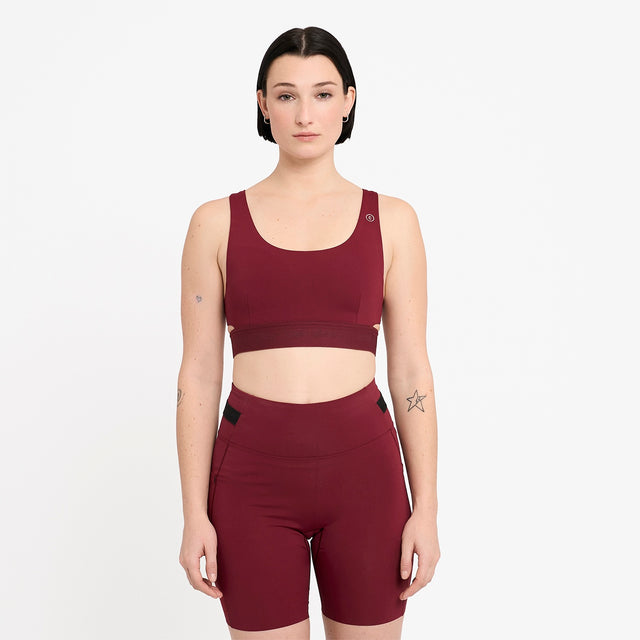 Woman wearing a Ciele Athletics Women's QCKBra Sports Bra in Crimson Red Maroon sports bra and shorts set on a white background