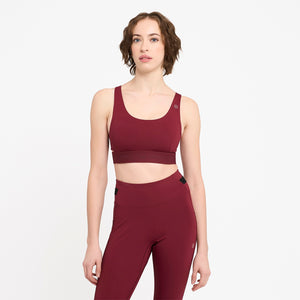 Woman wearing a Ciele Athletics Women's QCKBra Sports Bra in Crimson Red Maroon sports bra and leggings on a white background