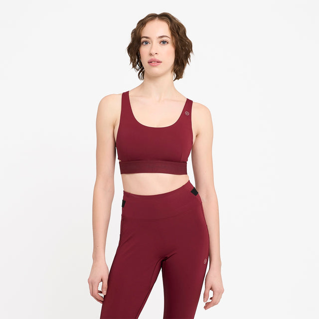 Woman wearing a Ciele Athletics Women's QCKBra Sports Bra in Crimson Red Maroon sports bra and leggings on a white background