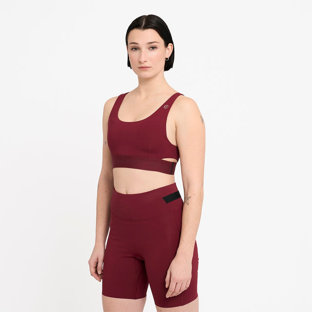 Woman wearing a Ciele Athletics Women's QCKBra Sports Bra in Crimson Red Maroon sports bra and shorts set on a white background